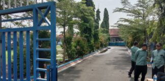 Para petugas keamanan berjaga di depan pintu pagar SMP Negeri 3 Comal, menghindar saat wartawan mengambil gambar