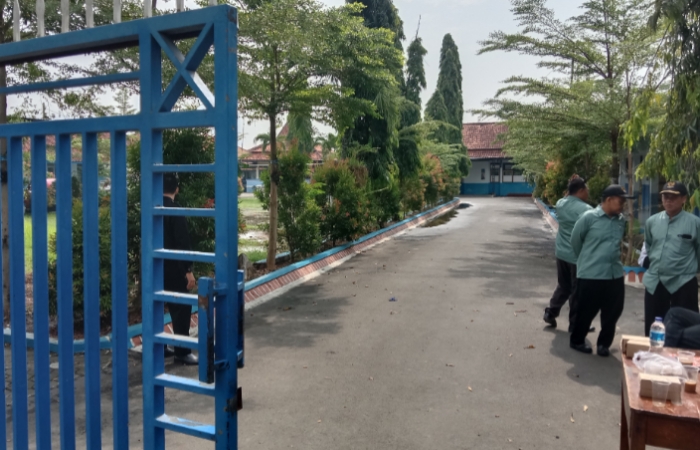 Para petugas keamanan berjaga di depan pintu pagar SMP Negeri 3 Comal, menghindar saat wartawan mengambil gambar